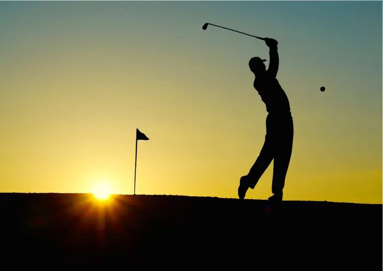 Golf club resting on green grass with a dawn sky in the background