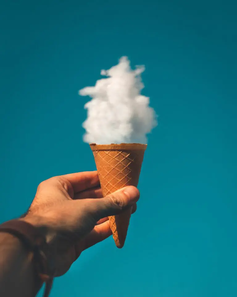Man holding ice cream cone under cloudy sky