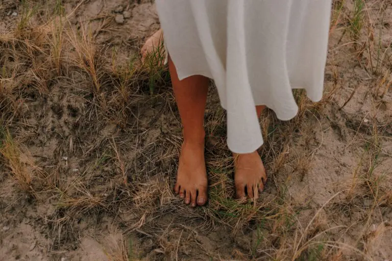 Person practicing morning grounding outside on grass under sunlight