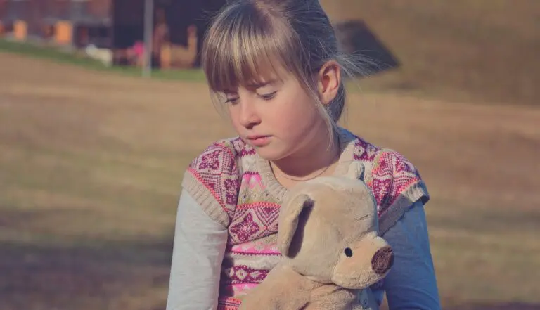 Child sitting with hands on head looking thoughtful