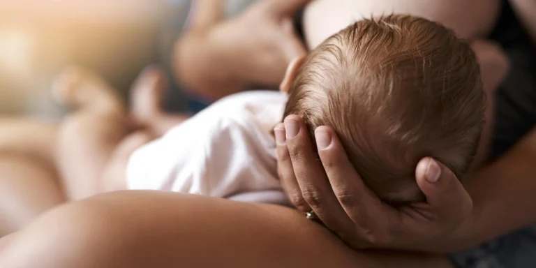Mother breastfeeding infant receiving chiropractic care assistance
