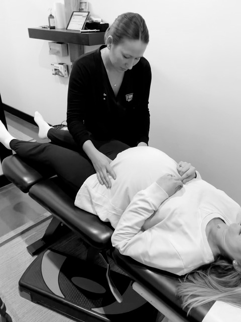 Chiropractor performing Webster prenatal chiropractic technique on pregnant woman