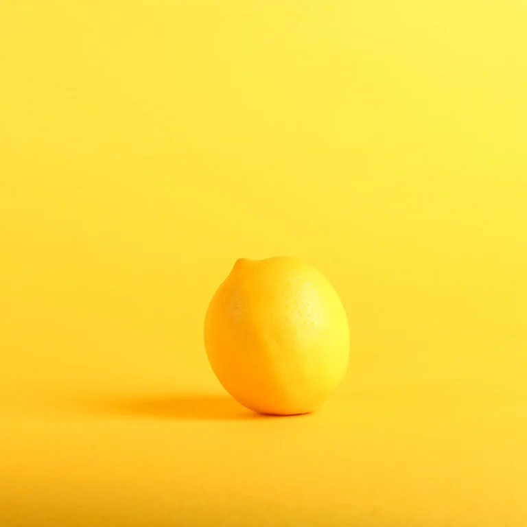 Glass of warm water with lemon slice on wooden surface