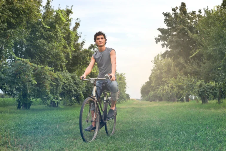 Man in gray sleeveless shirt riding a bike outdoors