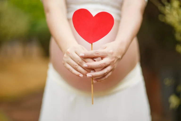 Pregnant woman gently holding her belly during prenatal care